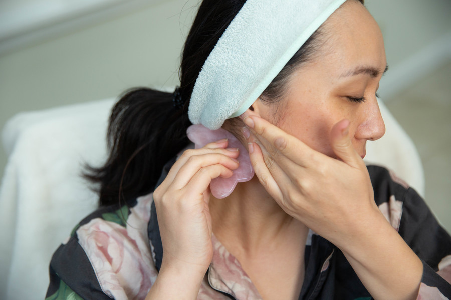 woman-in-kimono-performing-self-facial-massage-with-gua-sha-stone