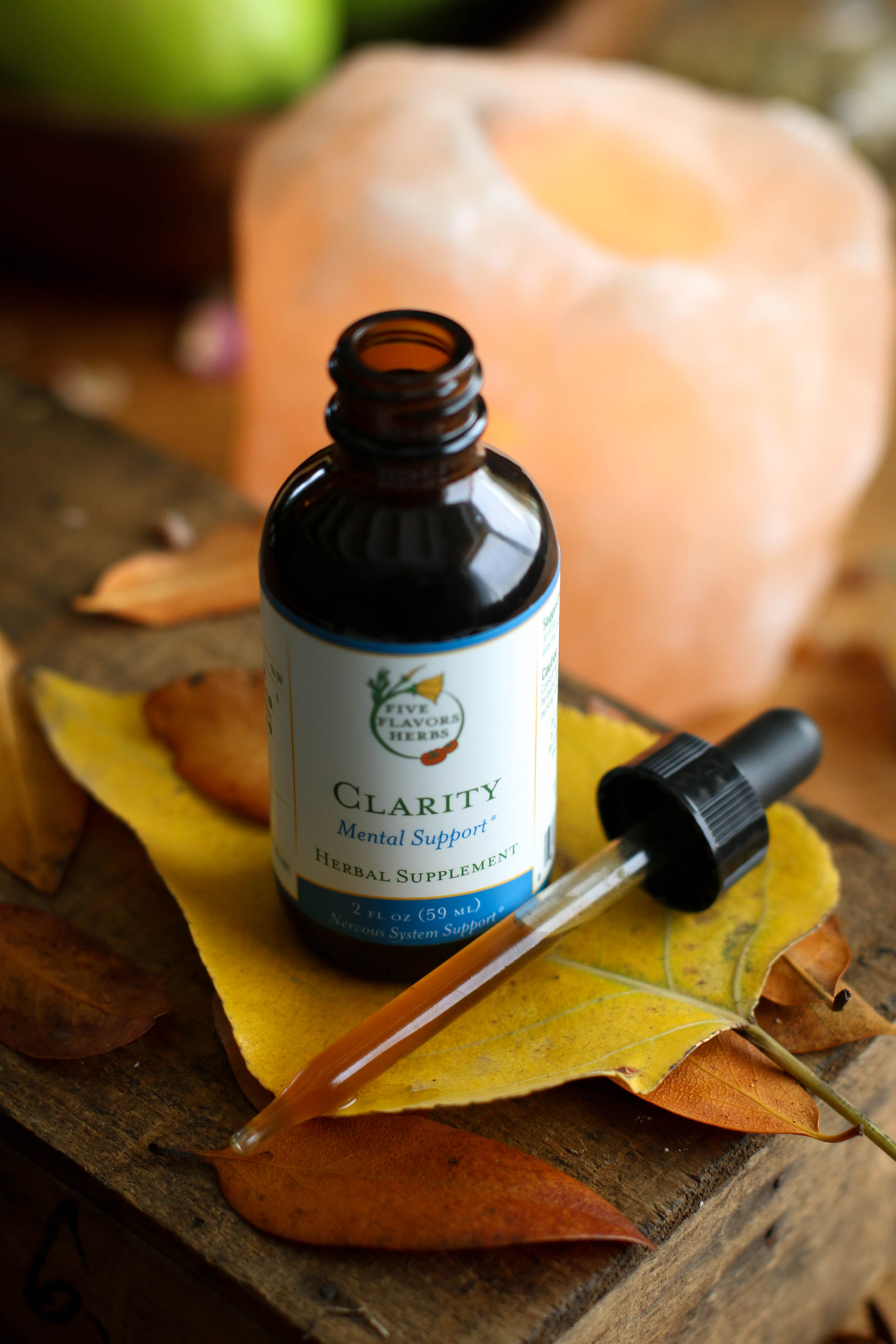 Bottle of Clarity herbal tincture with dropper next to himalayan salt on top of a leaf