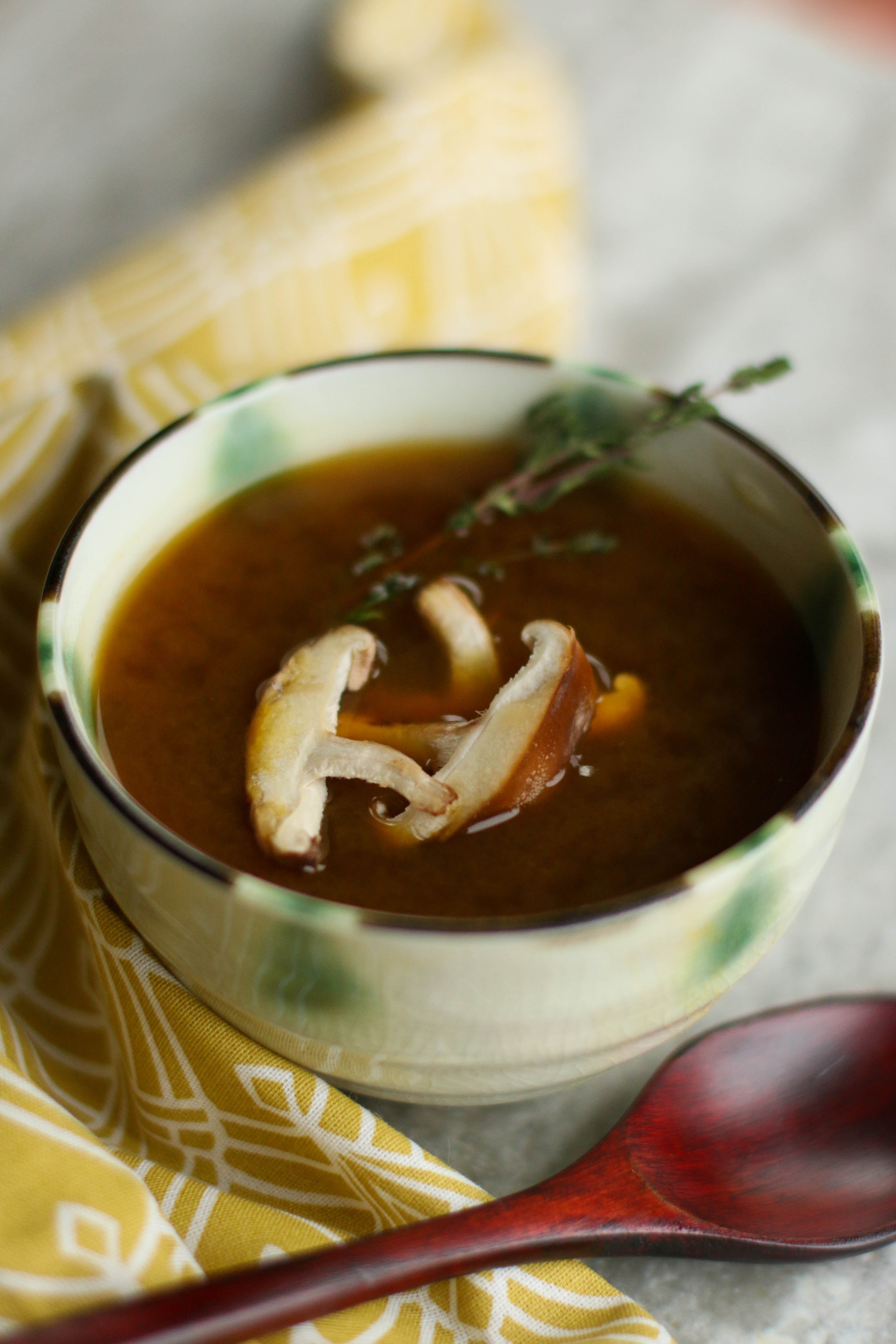 shiitake-mushrooms-and-thyme-in-broth-in-ceramic-bowl-with-wooden-spoon