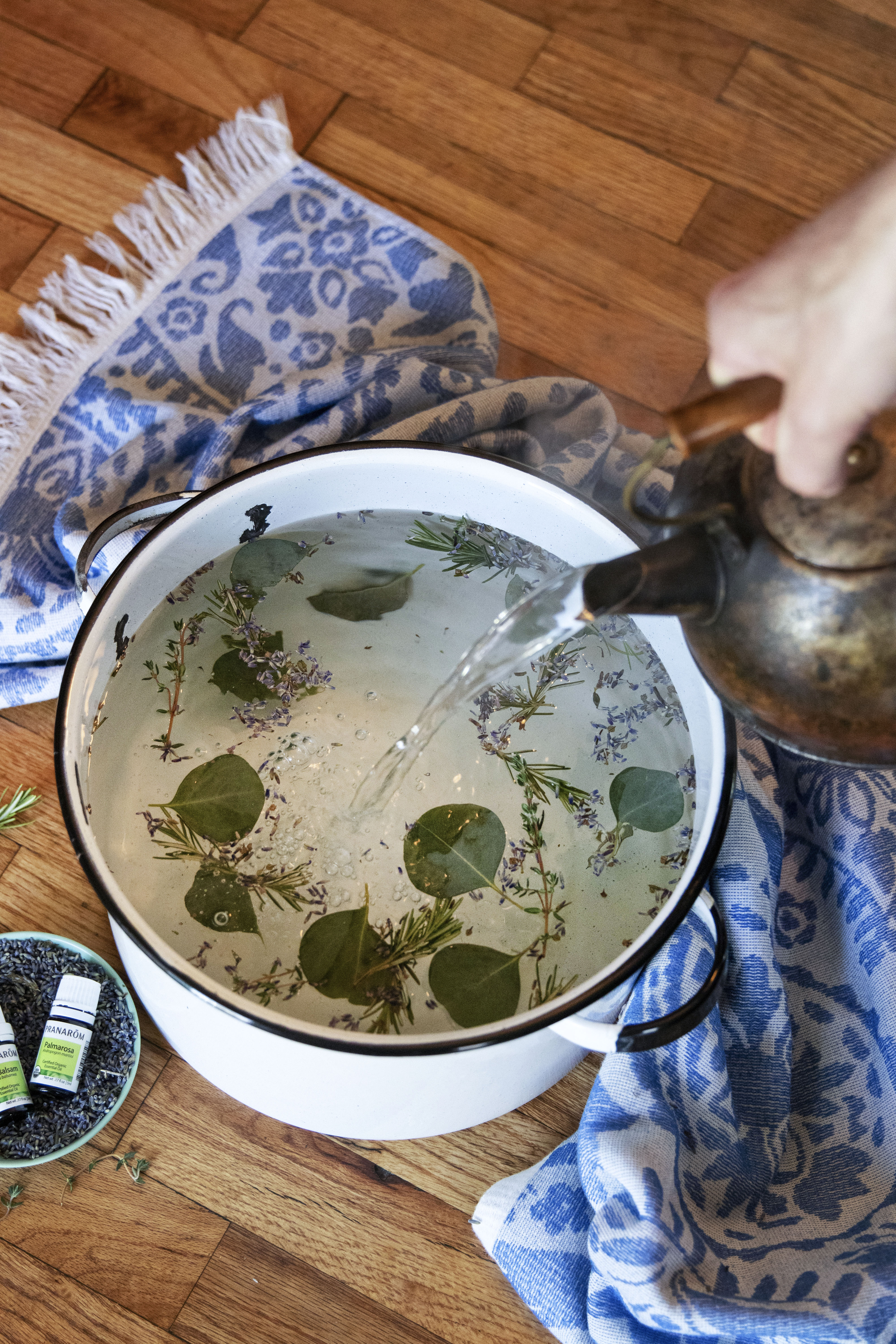 ceramic-basin-of-water-with-lavender-flowers-and-eucaplyptus-leaves-with-copper-kettle-pouring-in-hot-water-for-essential-oil-sinus-steam