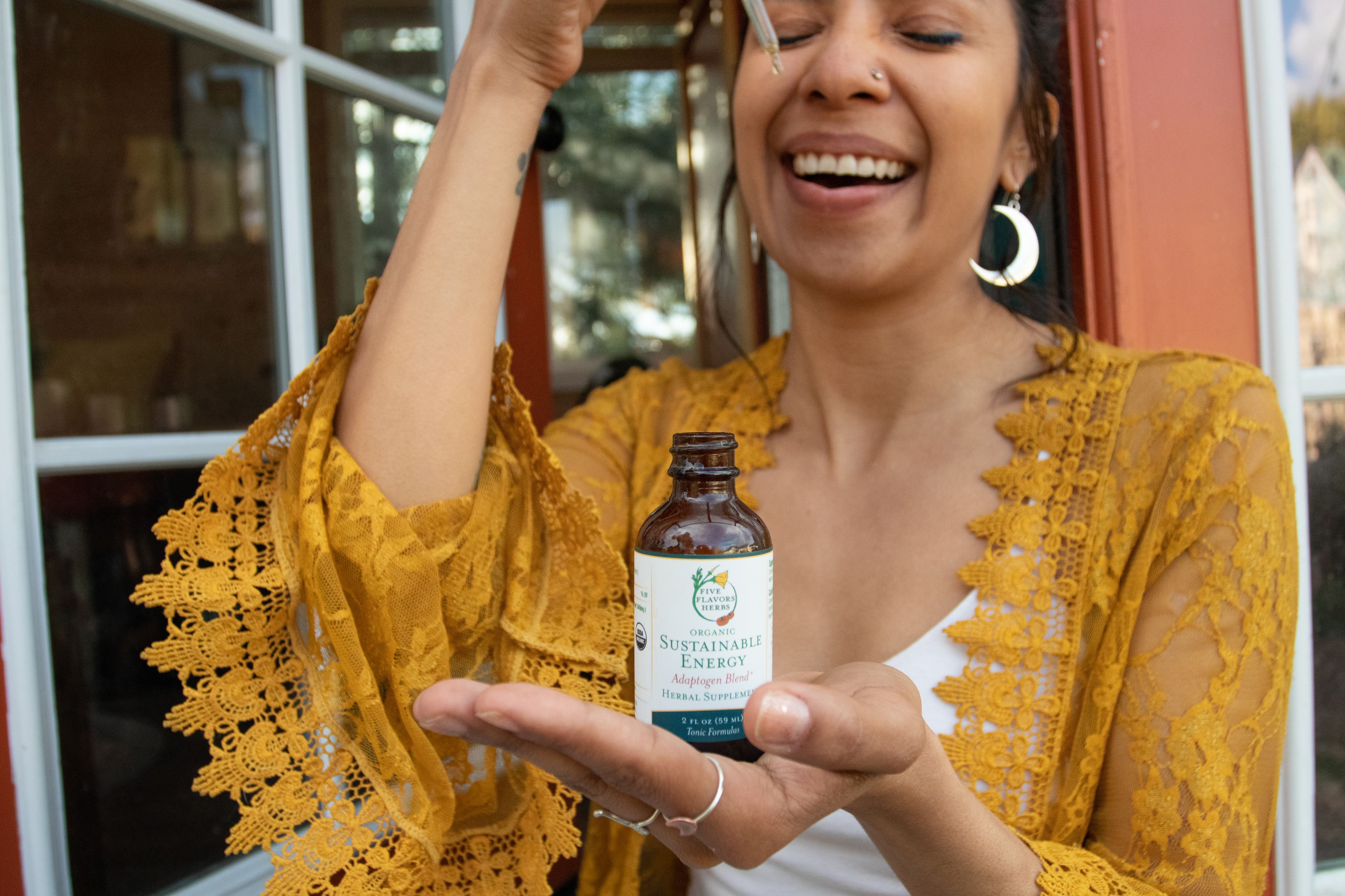 Woman in a yellow lace top taking a tincture