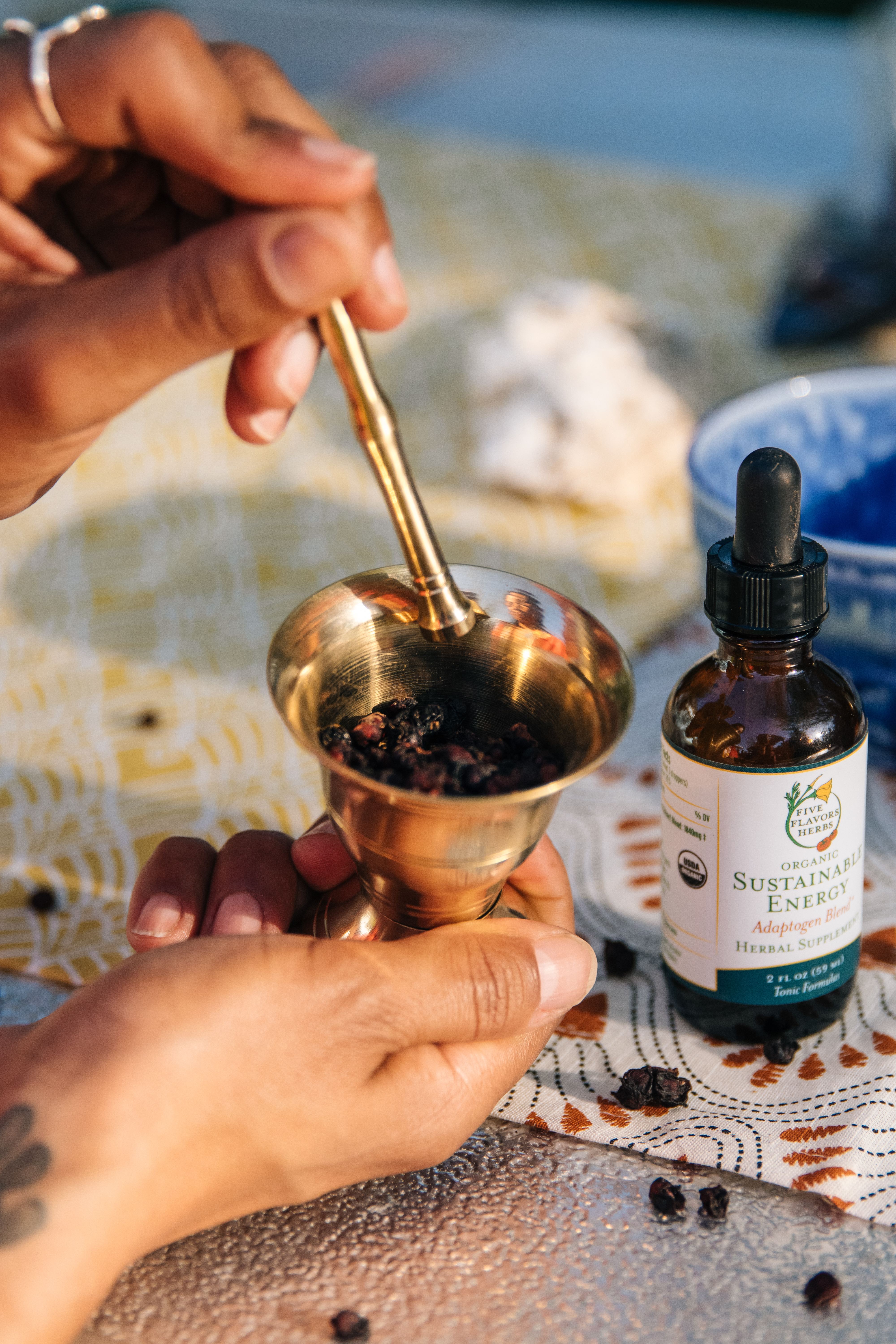 Woman using brass mortar and pestle and Sustainable Energy tincture