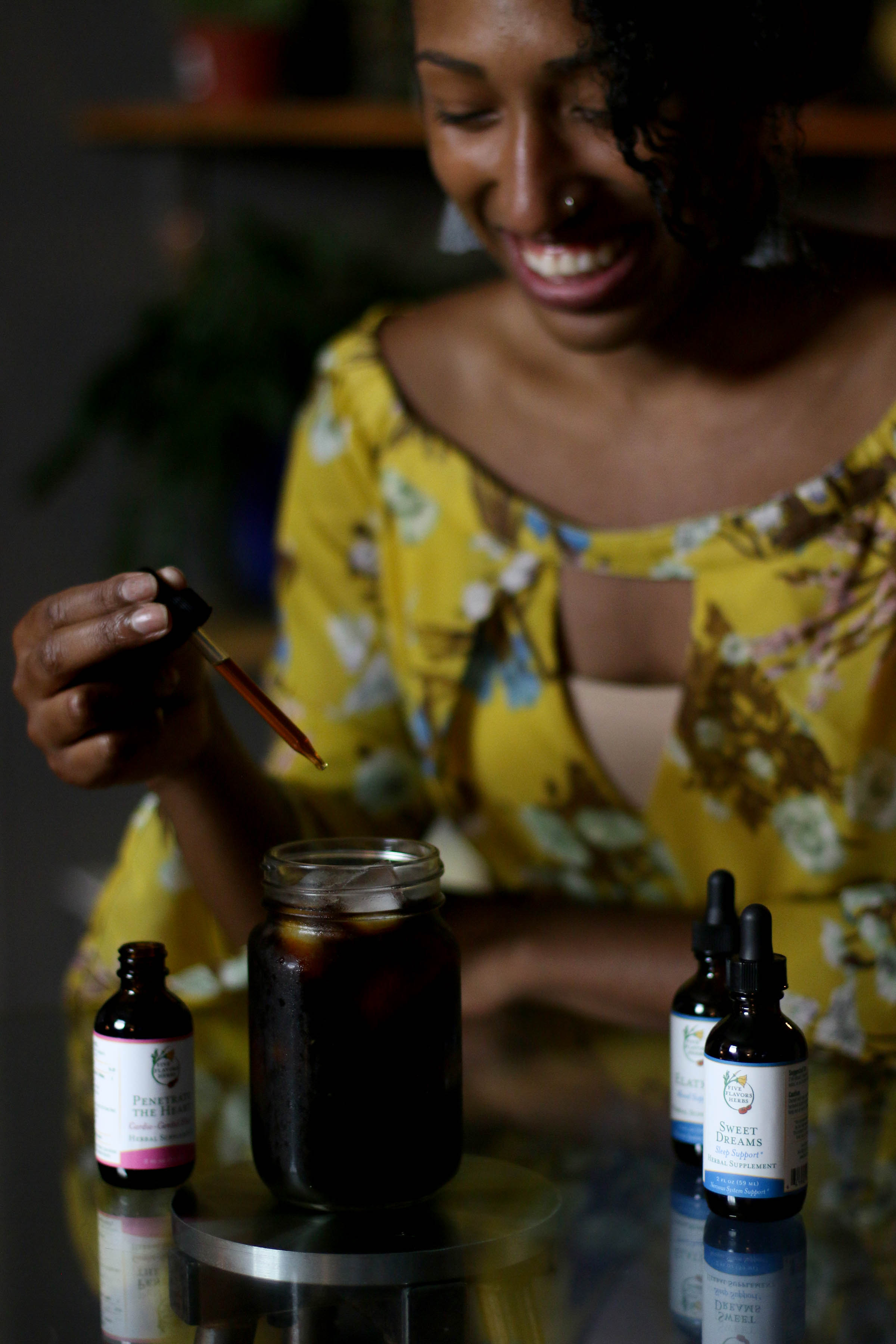 Woman putting dropper of tincture into glass of water