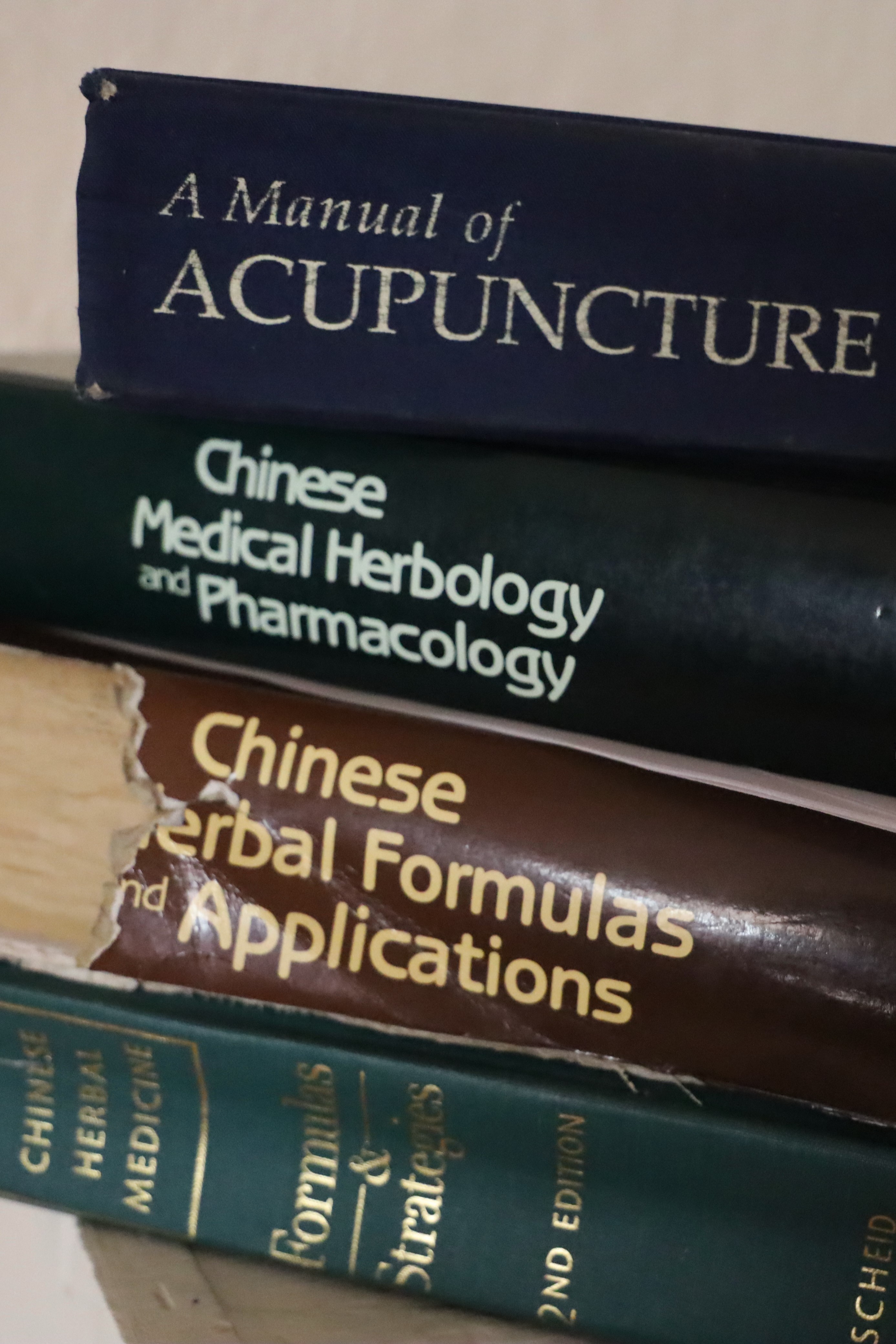 three-well-used-books-about-chinese-herbal-medicine-stacked-on-top-of-one-another