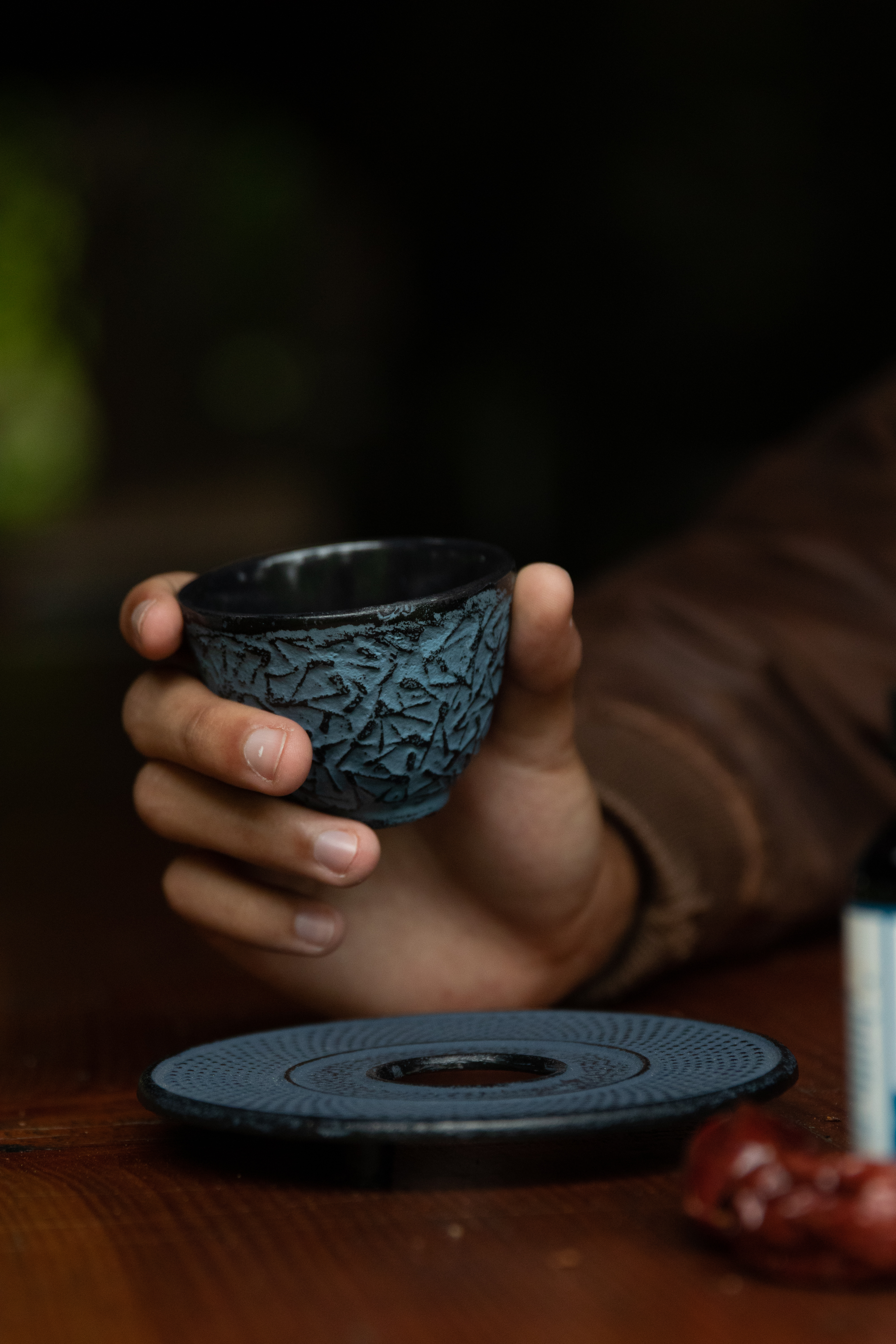 young-man-in-brown-leather-bomber-jacket-holding-blue-and-black-cast-iron-tea-cup-in-hand