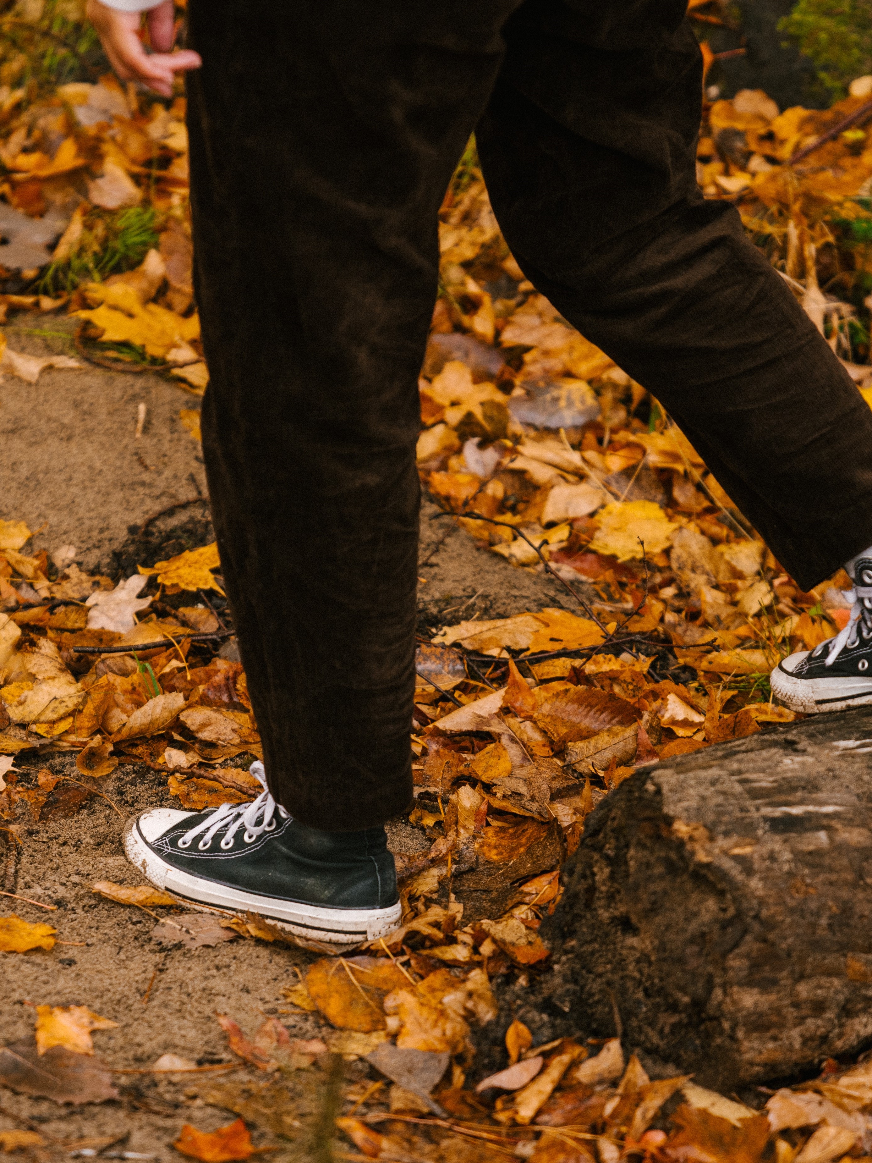 person-in-high-top-sneakers-walking-outside-over-autumn-leaves