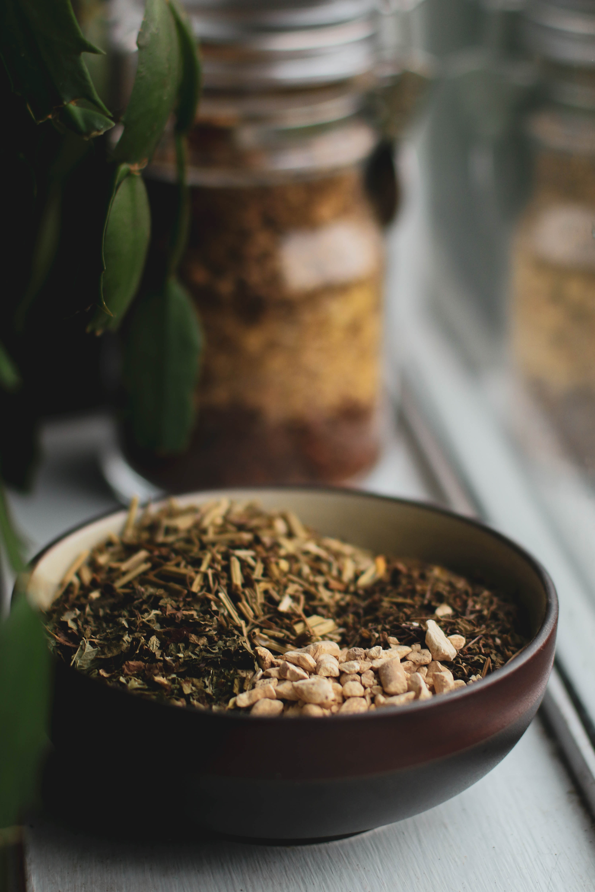 ashwagandha-root-holy-basil-tulsi-california-poppy-and-other-herbs-for-mood-in-a-bowl-with-glass-jar-of other-herbs-behind