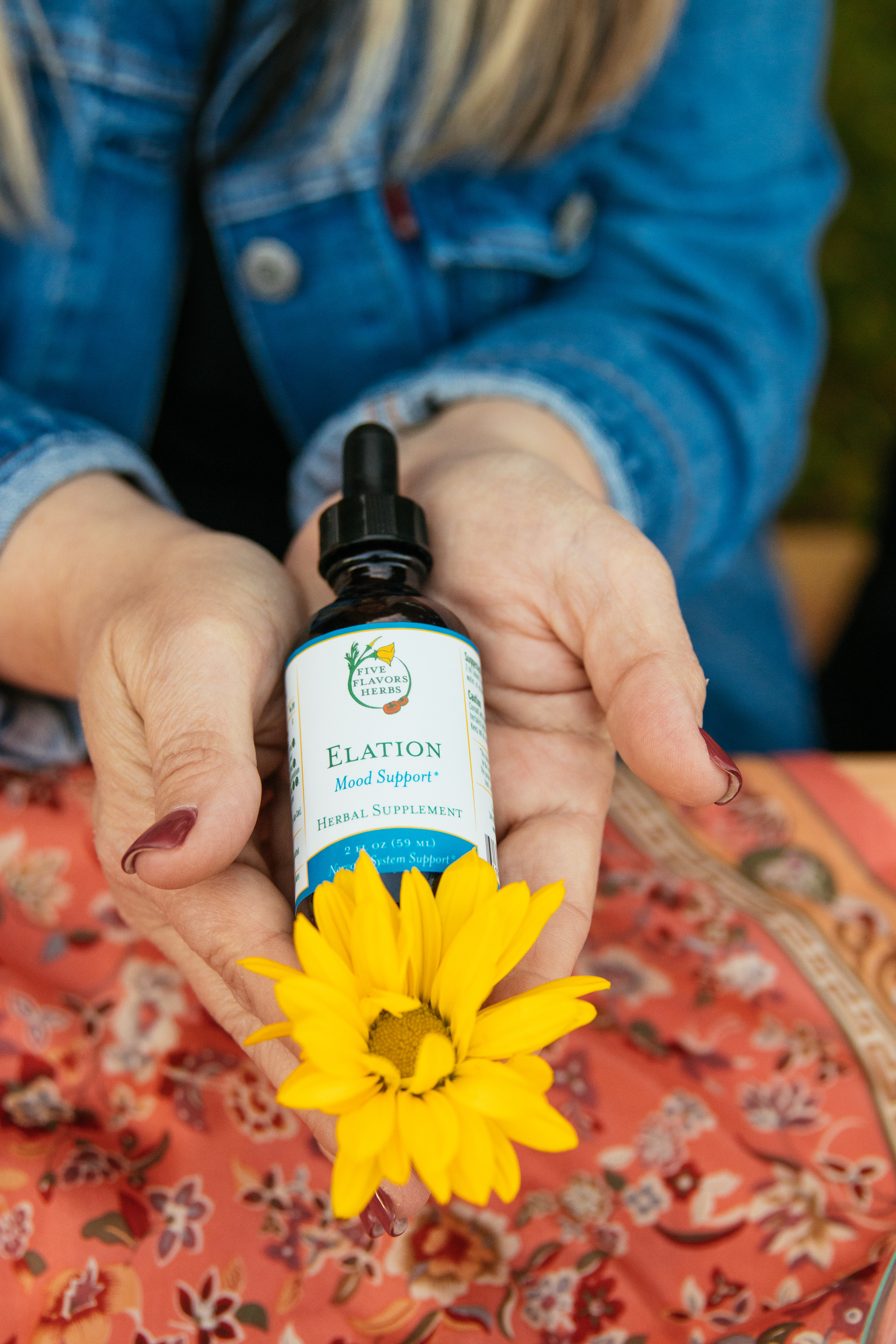 hands-holding-bottle-of-elation-mood-support-tincture-with-yellow-flower